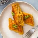 Turkish baklava pieces on a plate with pistachio topping.