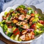 Turkish chicken salad (tavuk salata) with spiced grilled chicken, lettuce, tomatoes, cucumber, and red onion in a white bowl, with title text overlay.