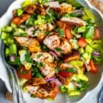 Turkish chicken salad (tavuk salata) with sliced spiced chicken, lettuce, cucumber, tomatoes, and red onion in a white serving bowl, with title text overlay.