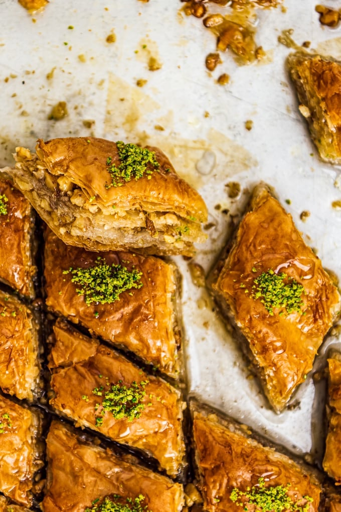 Walnut baklava slices topped with crumbled pistachio in a pan.