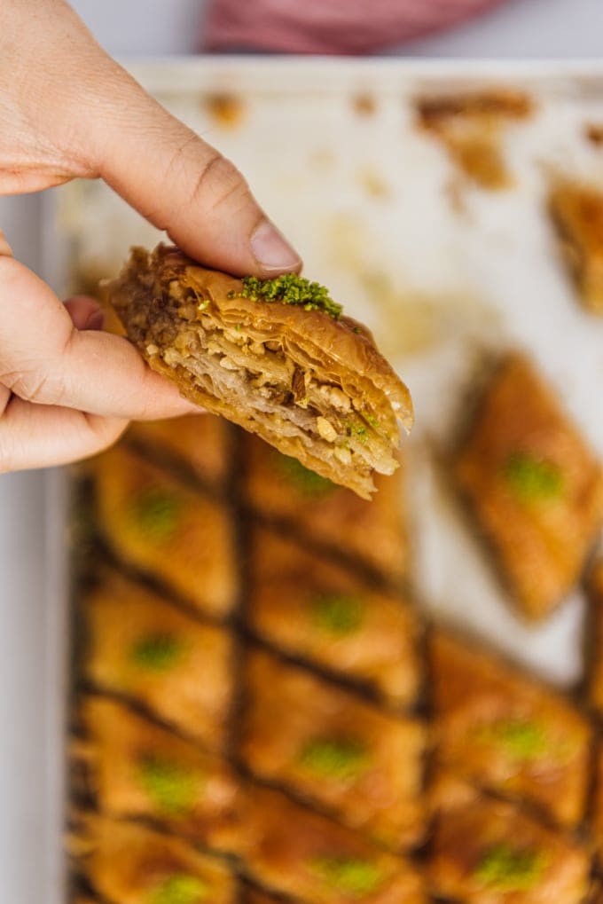 Woman holding a slice of homemade baklava with walnuts and pistachio