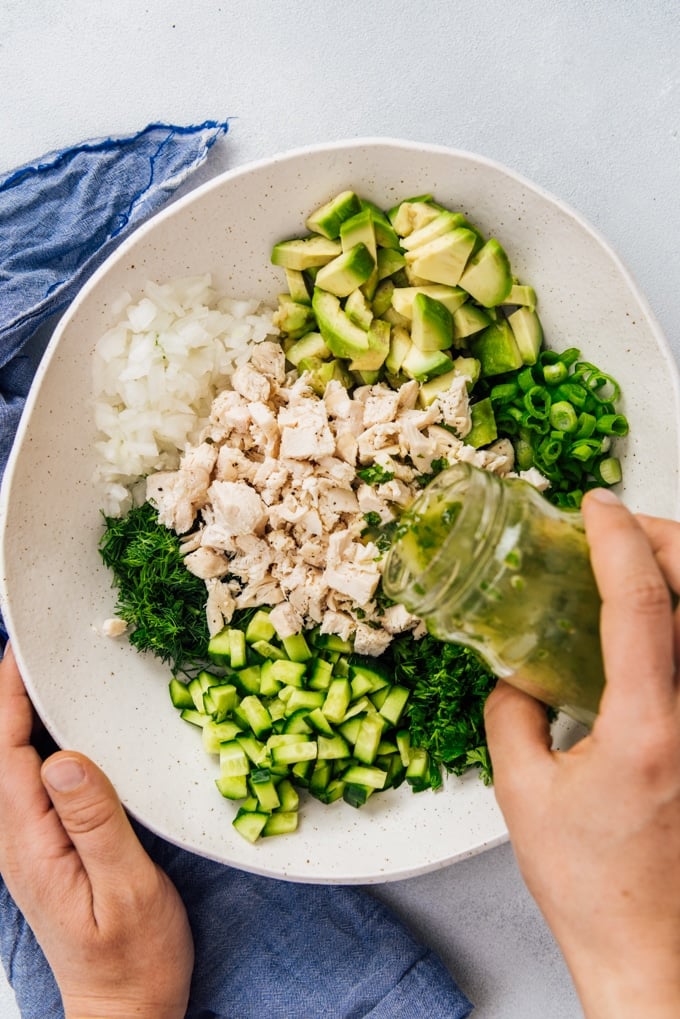 Pouring vinaigrette over chicken salad without mayo or dairy