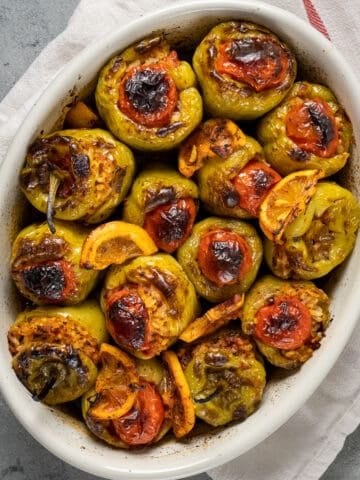 Baked rice stuffed green peppers in a white oval baking pan.