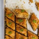 Newly baked Turkish baklava dessert filled with walnuts and topped with pistachio in a baking sheet