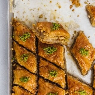 Newly baked Turkish baklava dessert filled with walnuts and topped with pistachio in a baking sheet