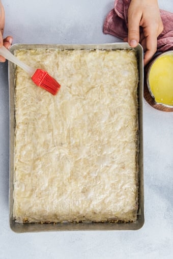 Spreading butter on phyllo sheets for a classic baklava recipe