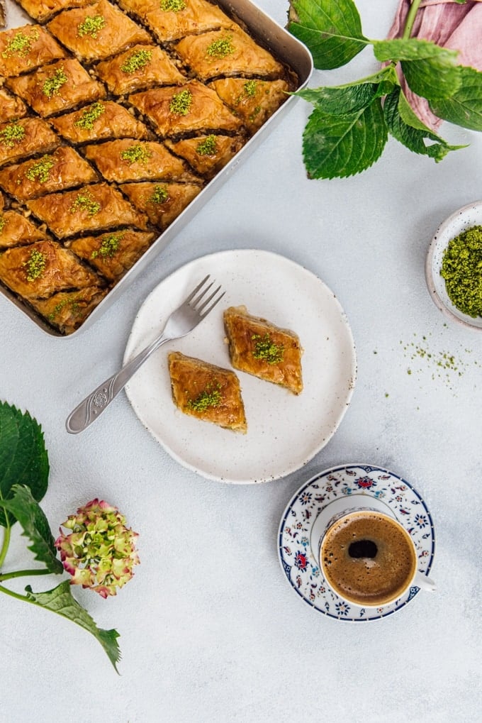 Turkish pastry baklava on a ceramic plate and in a traditional pan accompanied by Turkish coffee