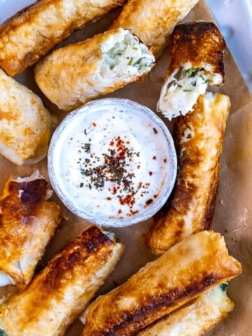 Feta rolls served with a small bowl of yogurt dip in the middle.