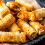 Turkish sigara boregi, crispy fried phyllo rolls filled with cheese and herbs, served on a plate.