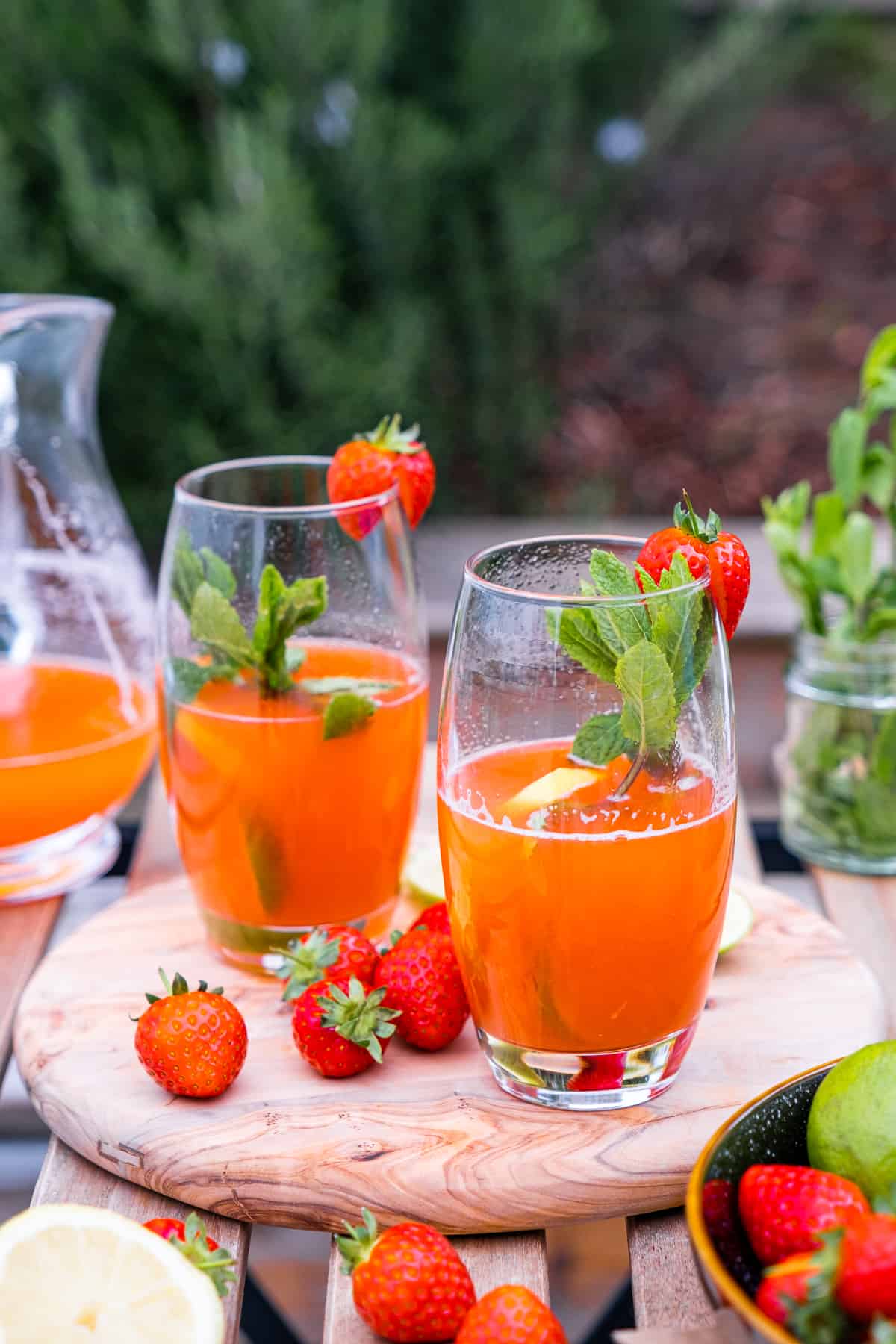 Strawberry lemonade in tall glasses garnished with mint leaves, strawberries and lemon leaves.
