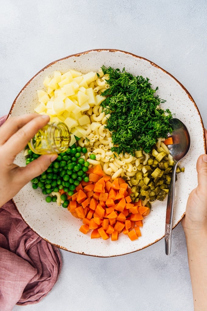 making classic macaroni salad with veggies in a ceramic bowl