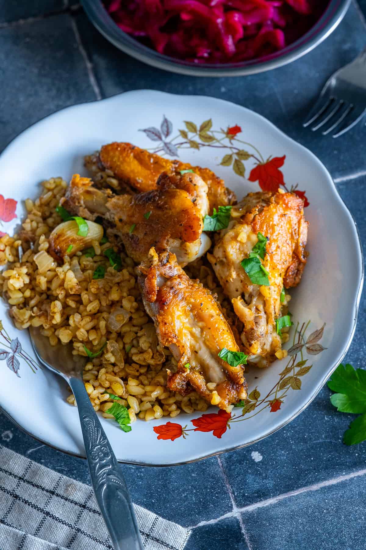 Close-up of golden chicken wings with bulgur, garlic and fresh parsley.
