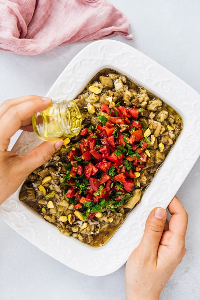 Turkish Eggplant Salad is the yummiest summer lunch when combined with a tangy dressing and topped with fresh summer tomatoes. #eggplantrecipe #eggplant #roastedeggplant #turkishsalad #turkishrecipe Drizzling olive oil over roasted eggplant salad turkish