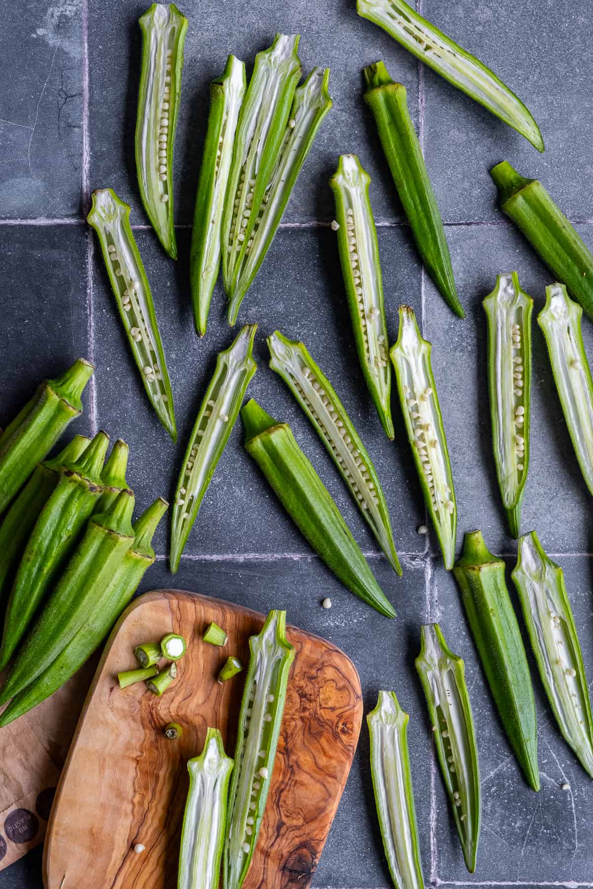 Okra pods sliced lengthwise on grey tiles.