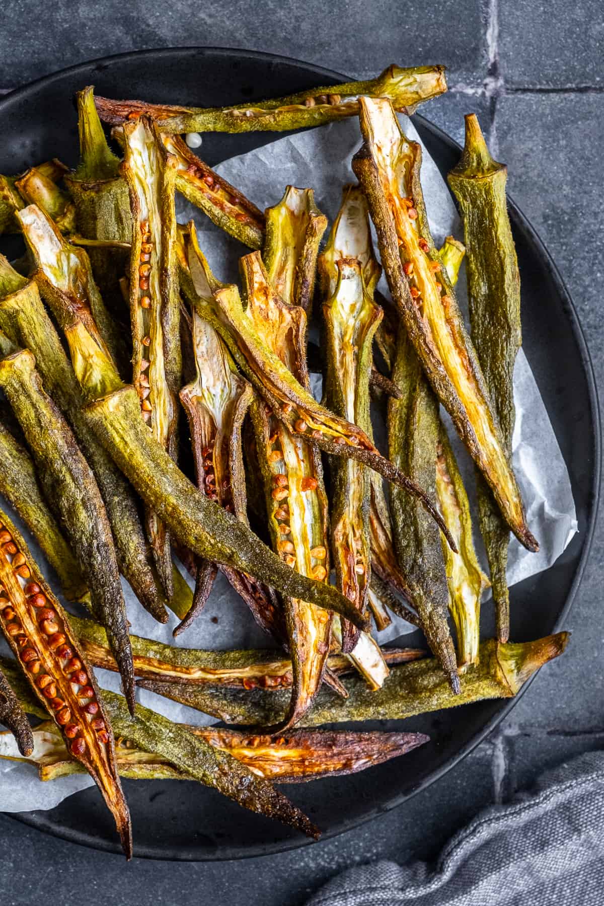 Okra chips piled on a black plate.