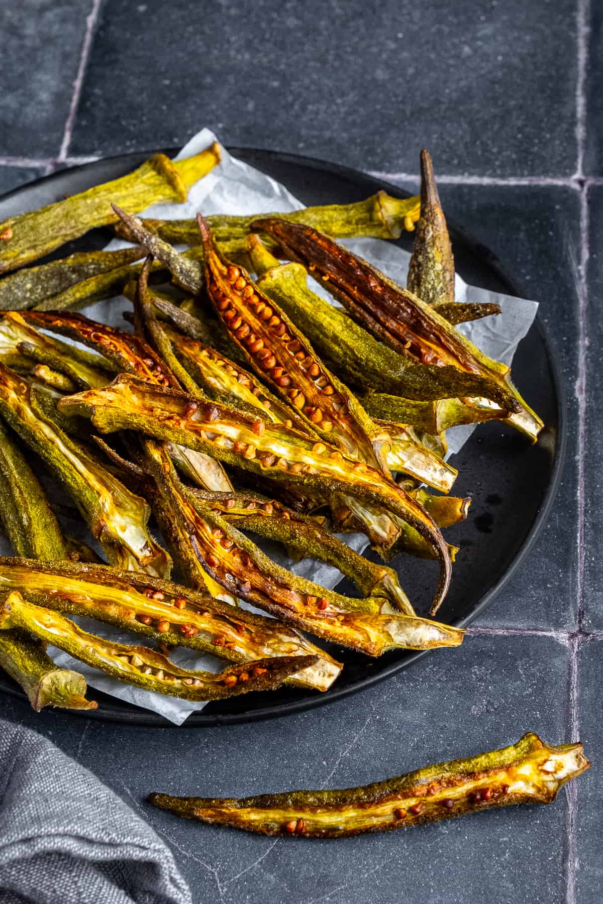 Crispy okra chips on a black plate.