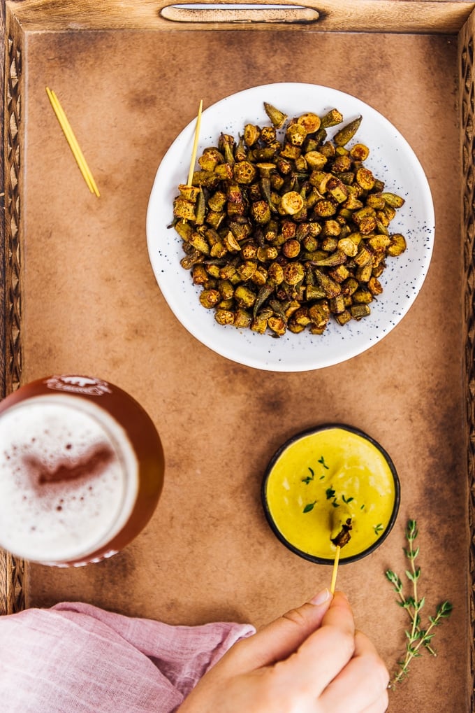 Oven roasted Okra Recipe is for those who hate okra. These crispy roasted okra chips will become their new favorite snack. Healthy and incredibly tasty! #roastedokra #okrarecipe #healthysnack Roasted okra chips served with turmeric tahini dip and a glass of beer.