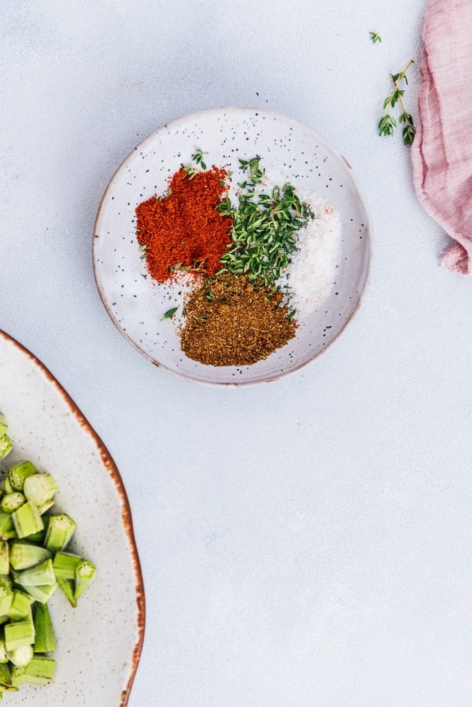 Spice mix for roasted okra chips in a mini ceramic bowl on a light background.