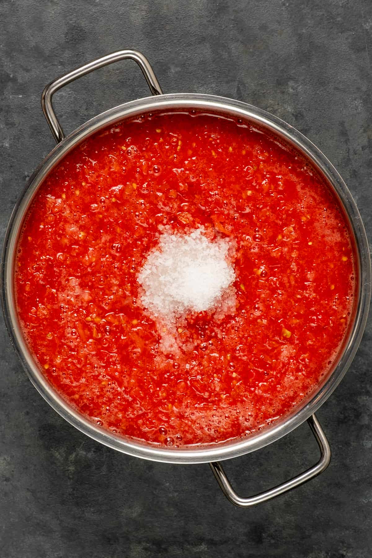 Pureed tomatoes in a deep pot, some kosher salt on the top.