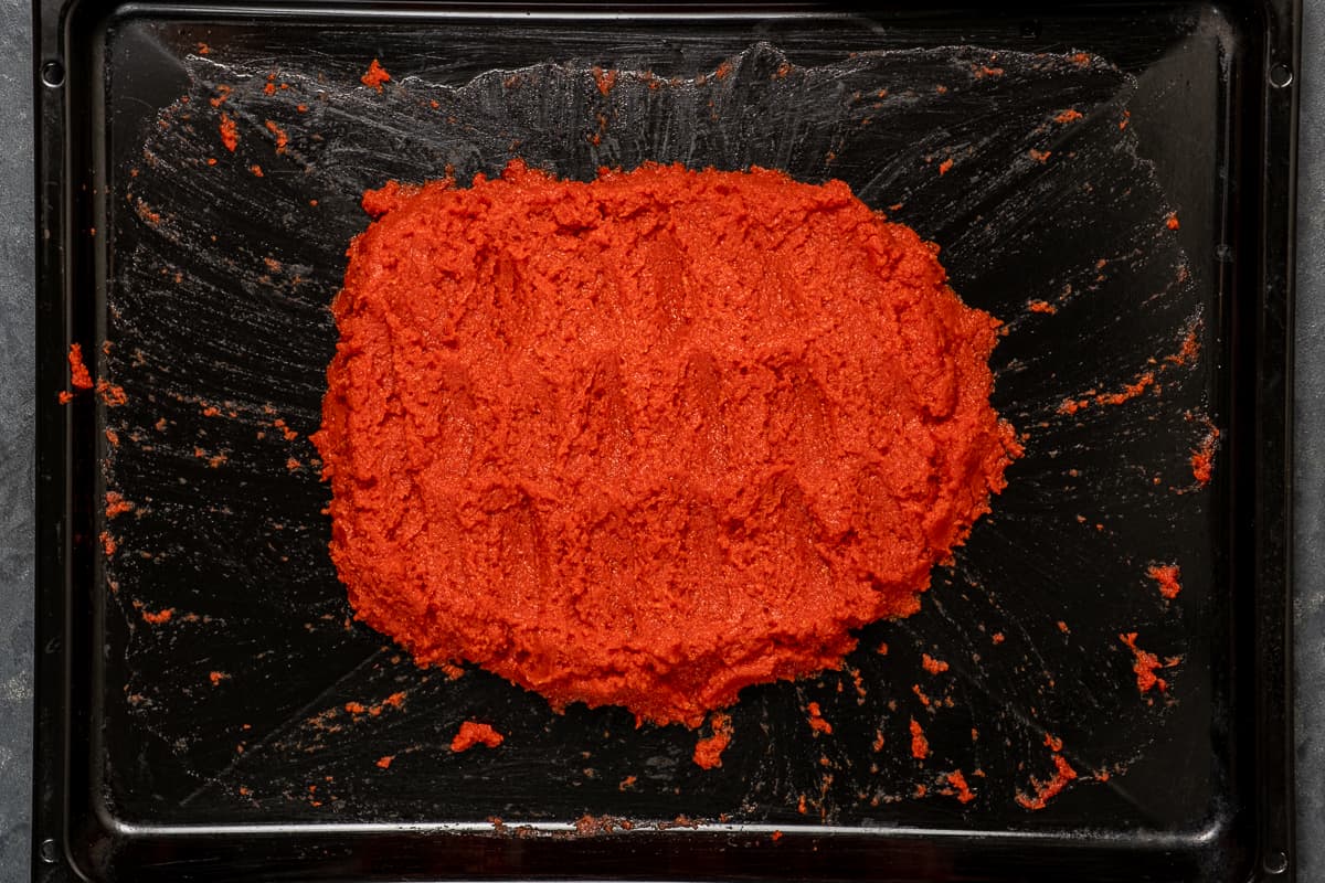 Reduced and thickened tomato paste on a baking sheet.