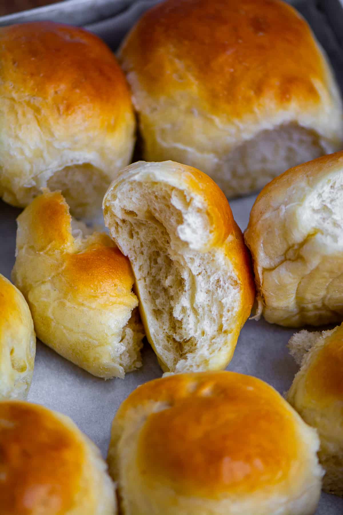 A close shot of homemade bread rolls, one is halved.