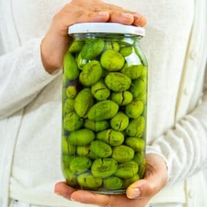 Woman hands holding a jar of green olives.