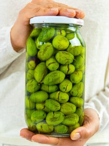 Woman hands holding a jar of green olives.