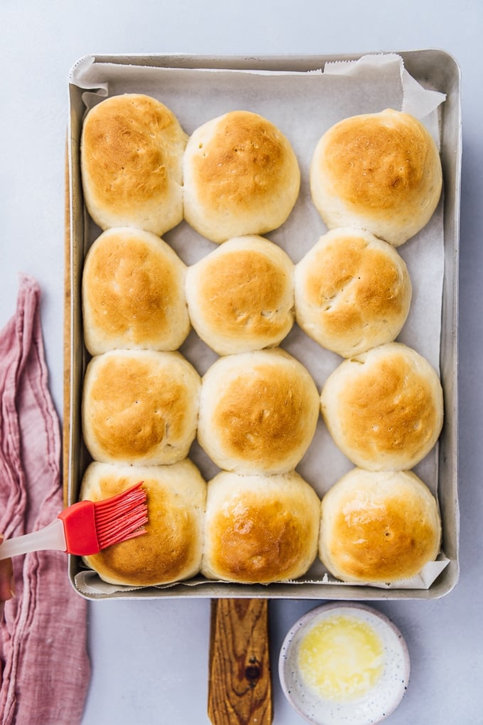 These classic homemade dinner rolls are wonderfully SOFT and fluffy. The best recipe that works perfectly every time! #dinnerrolls #yeastrolls #bakingbread #breadrollrecipe brushing newly baked yeast rolls with melted butter