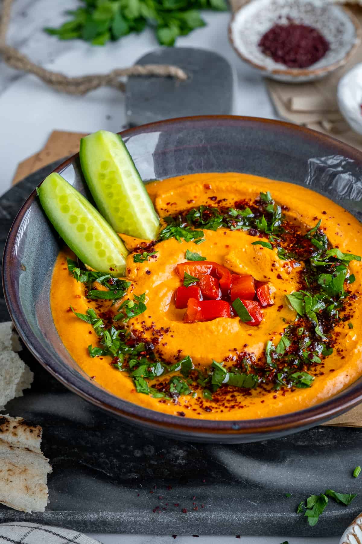 Red pepper hummus topped with chopped parsley, chopped roasted red peppers and spices.