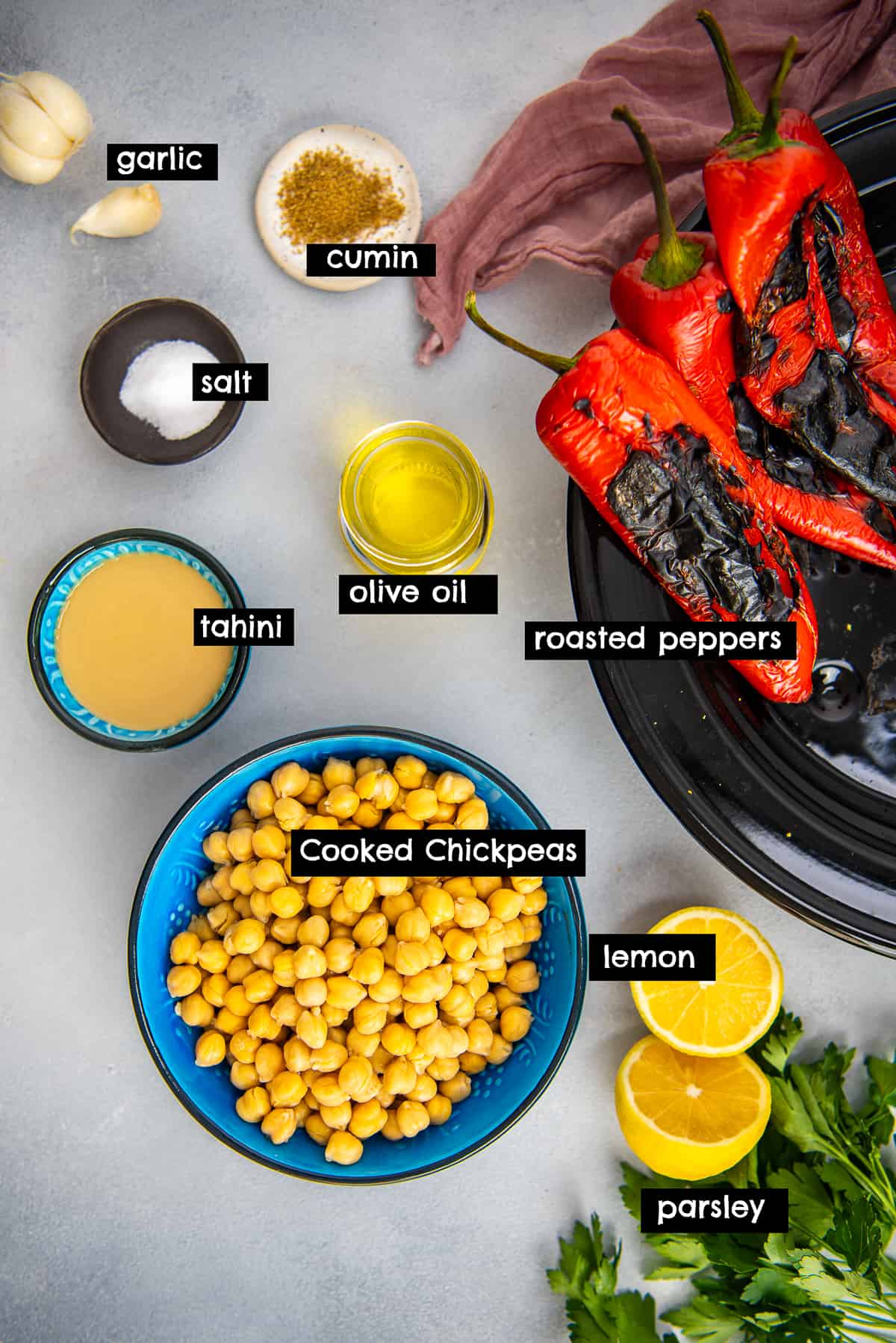 Roasted peppers, chickpeas, tahini, olive oil, lemon, parsley, garlic, salt and cumin photographed from top view.