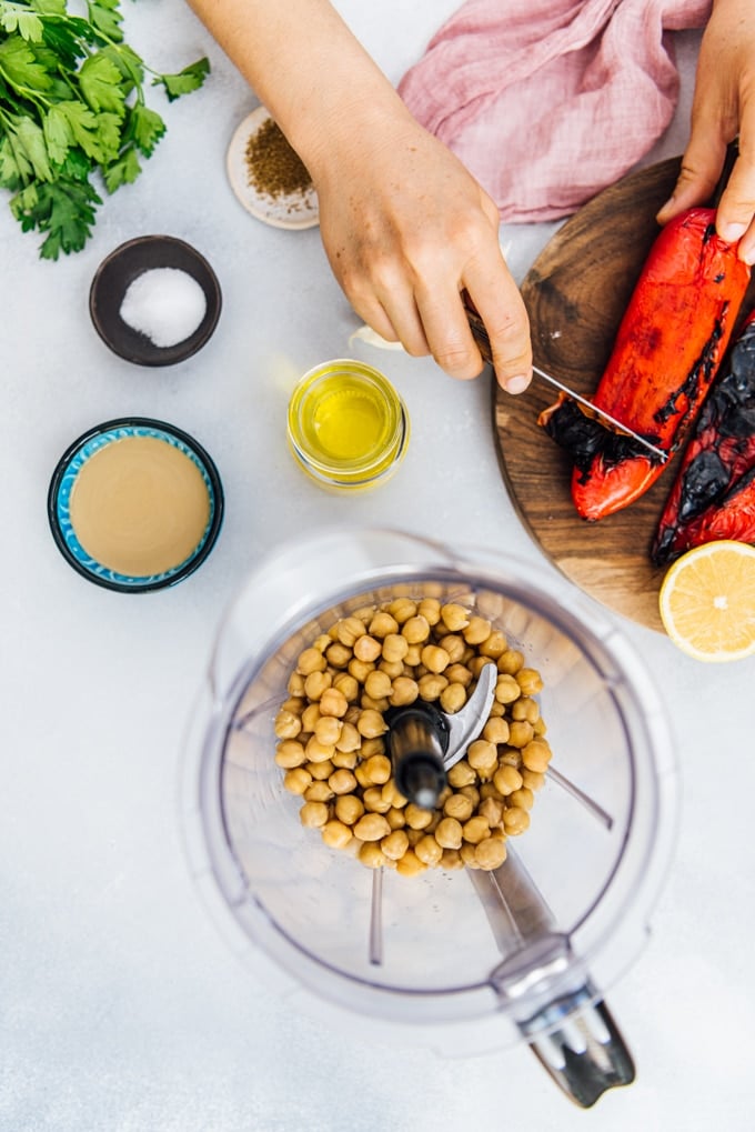 Peeling roasted red bell peppers and other ingredients to make red hummus dip.