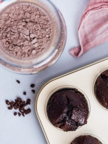 Chocolate cake mix in a jar and chocolate muffins in a muffin pan photographed from top view.