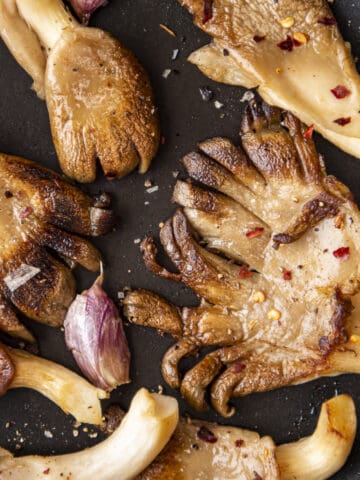 Oyster mushrooms cooked in a non-stick pan with garlic cloves until golden.