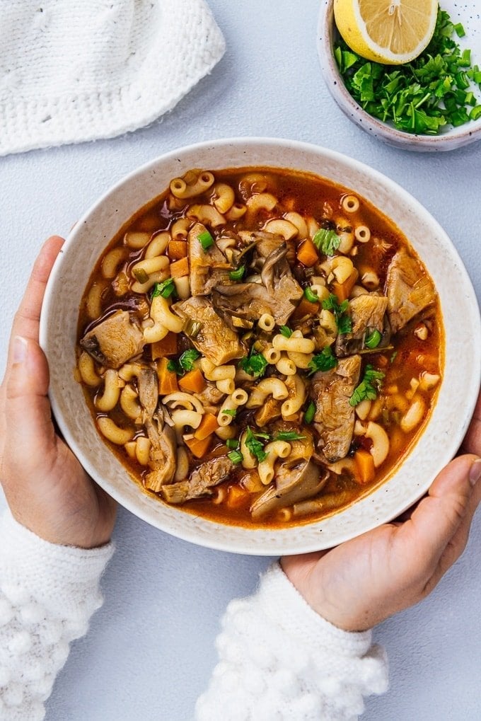 Woman holding a bowl of fresh oyster mushroom soup