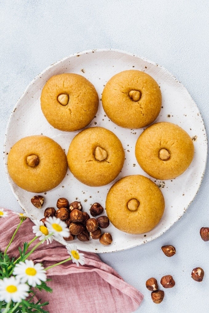 Middle Eastern syrup soaked semolina cookies sekerpare dessert topped with hazelnuts on a white plate