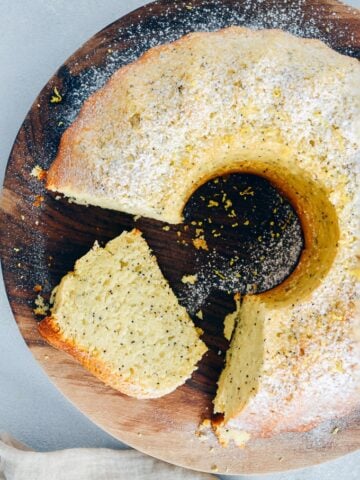 Lemon poppy seed cake sliced on a wooden stand.