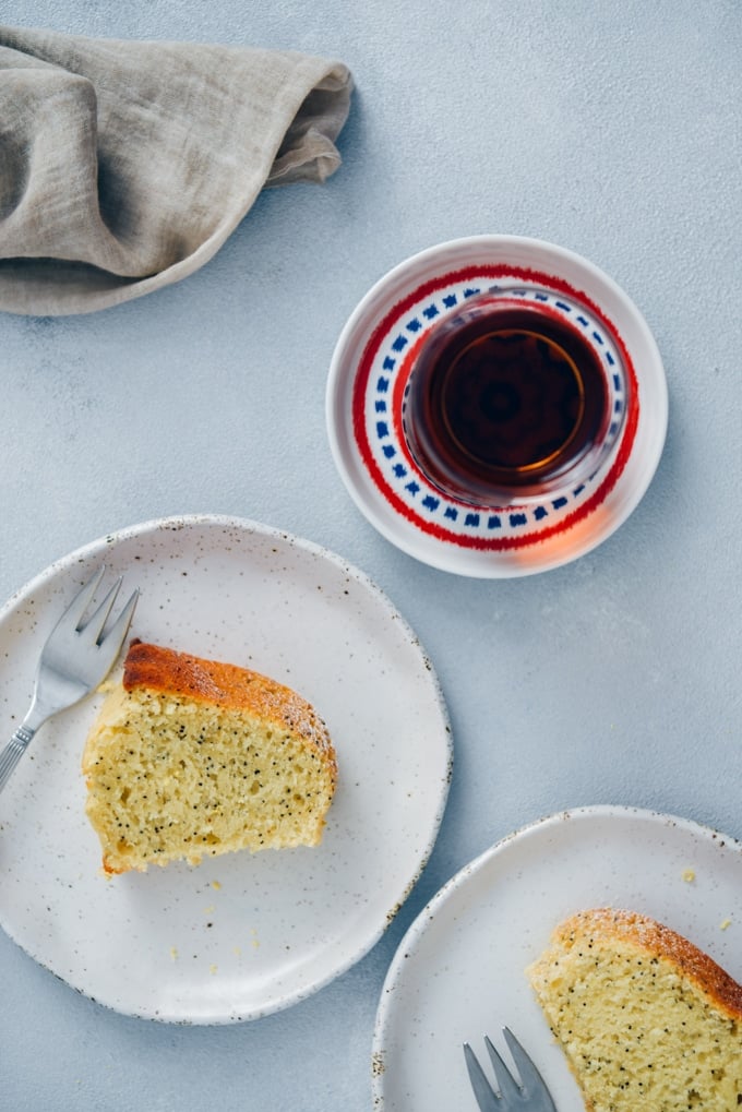 Slices of lemon poppy seed cake served on white ceramic plates accompanied by a glass of Turkish tea.