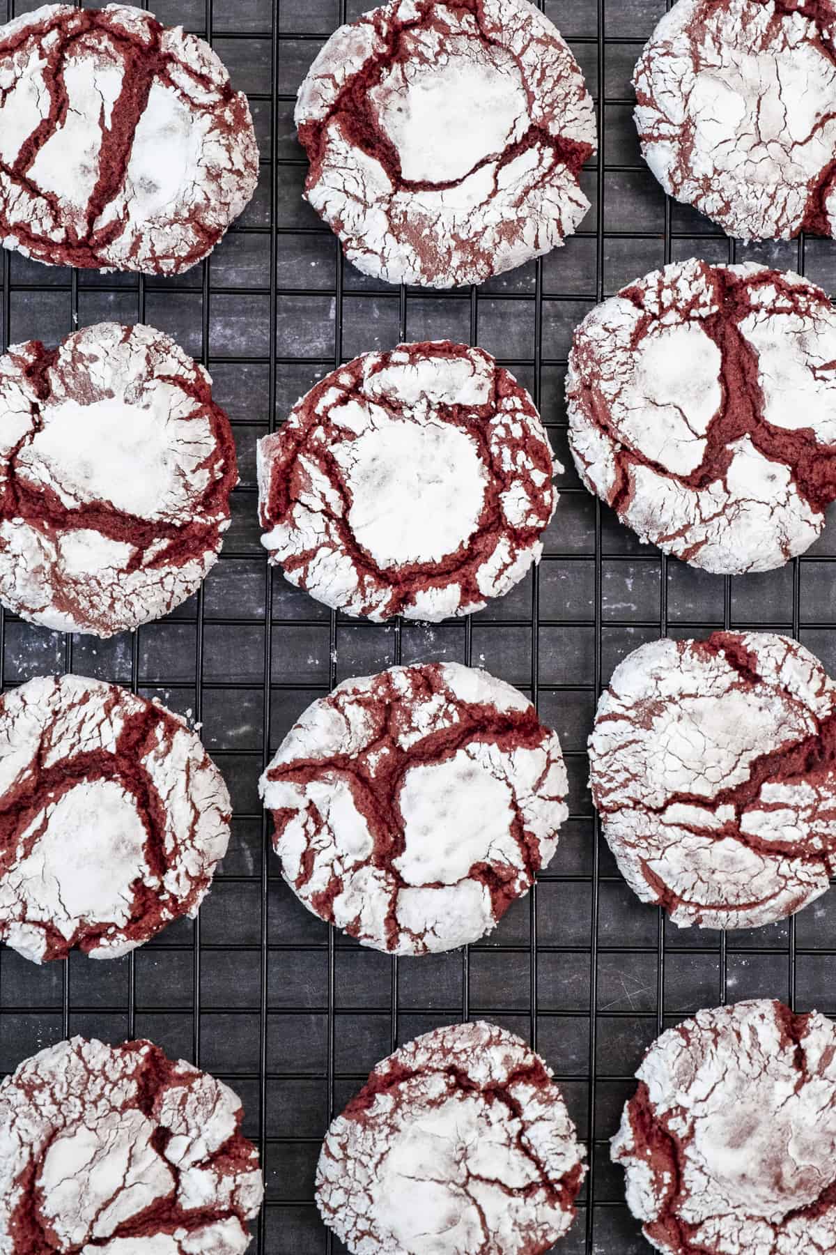 Red velvet crinkles on a cooling rack on a dark background.