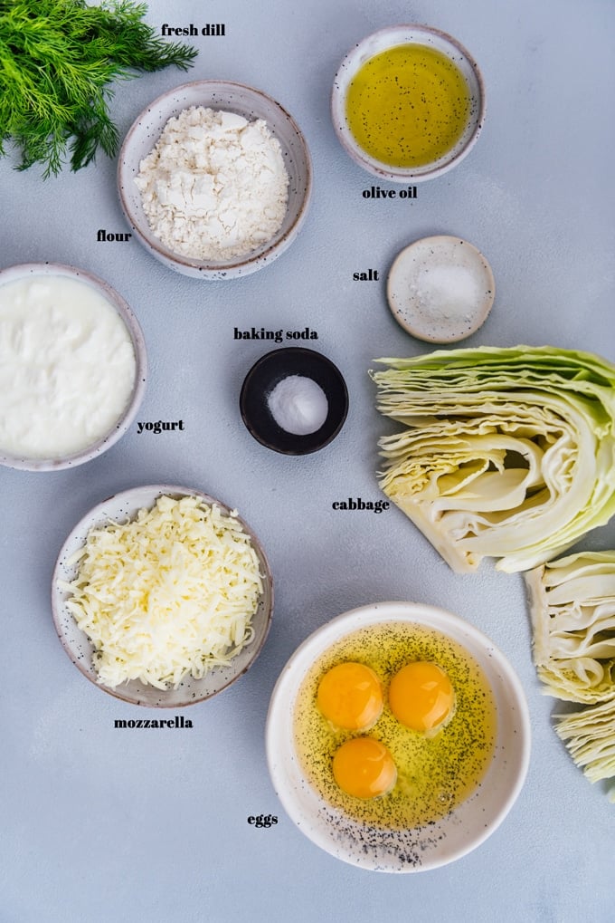 Cheesy cabbage ingredients in ceramic bowls on a grey background