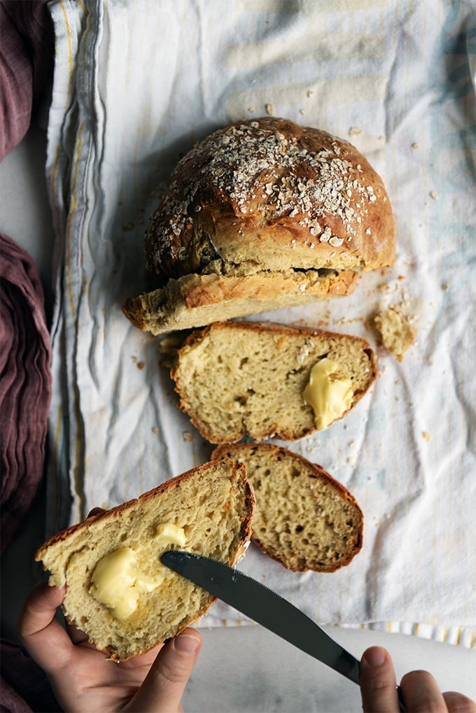 Spreading butter on a slice of homemade bread made without yeast.