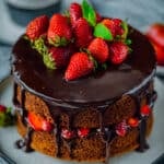 Chocolate cake with whole strawberries and chocolate ganache on the top.