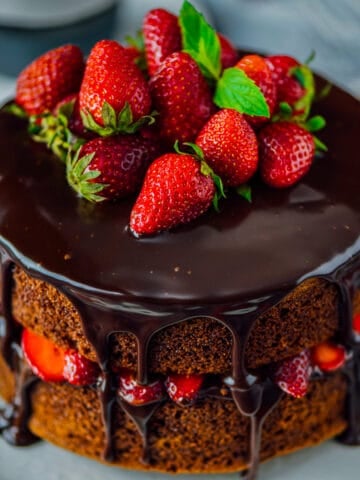 Chocolate cake with whole strawberries and chocolate ganache on the top.