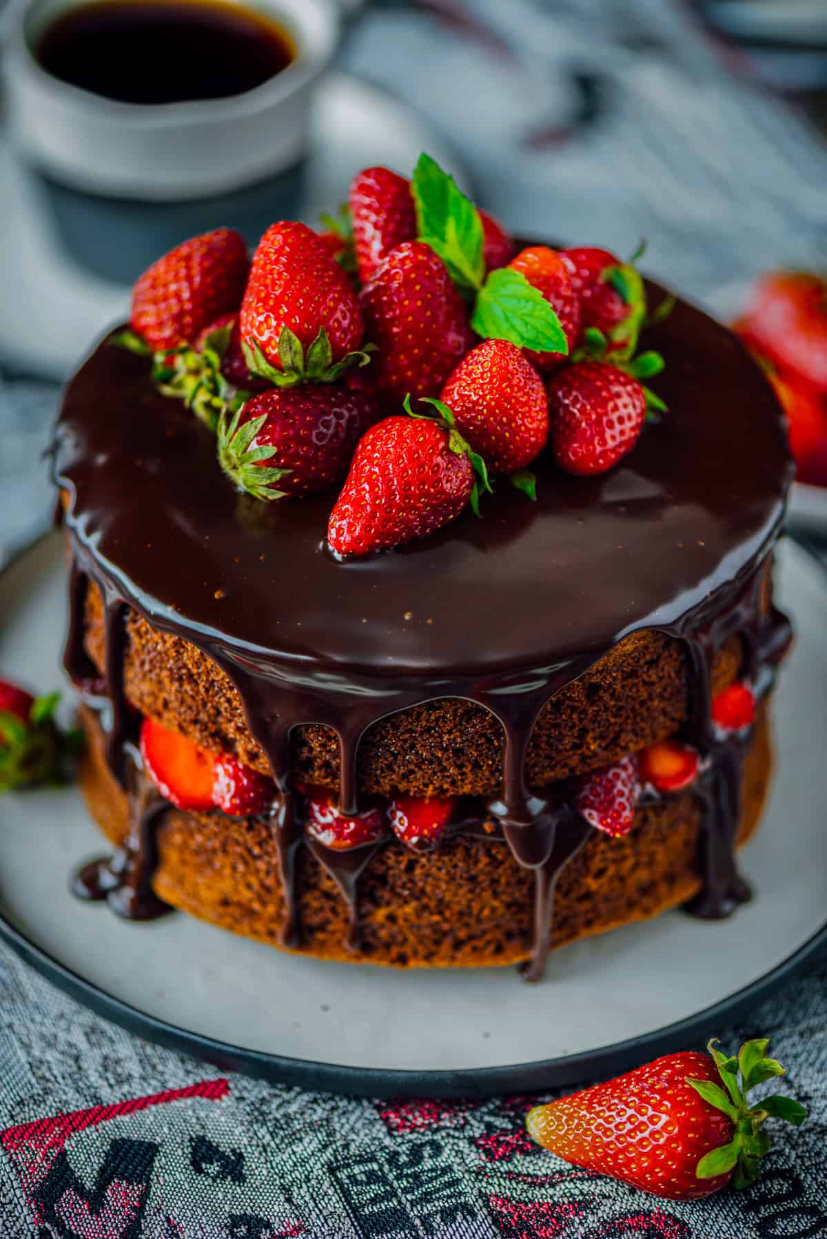 Chocolate cake with ganache and whole strawberries on the top.