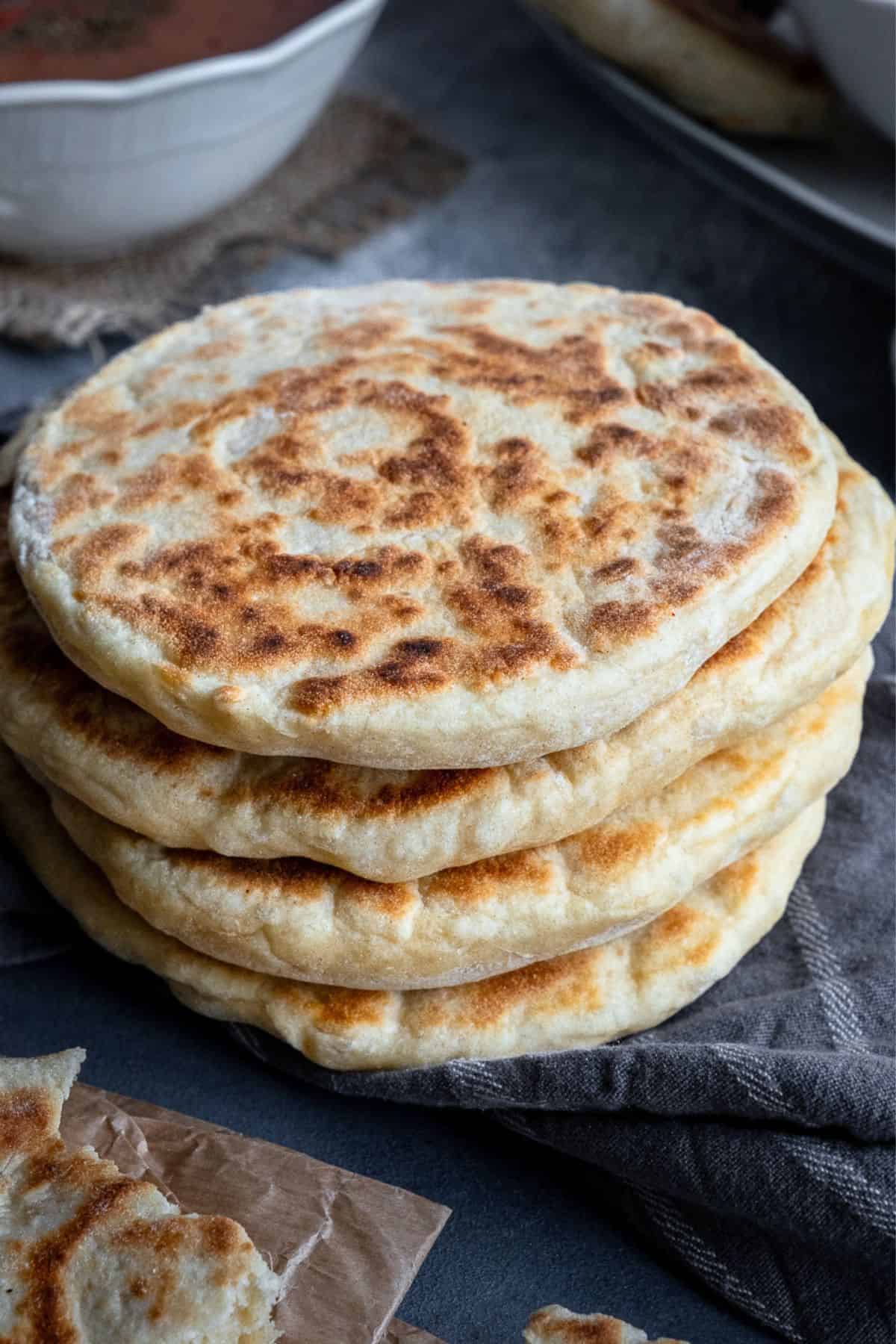 Stack of soft, golden bazlama flatbreads with a fluffy texture.