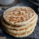 Stack of soft, golden bazlama flatbreads with a fluffy interior, served warm.