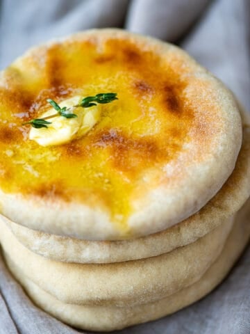 A stack of bazlama breads, melting butter and thyme on the top.