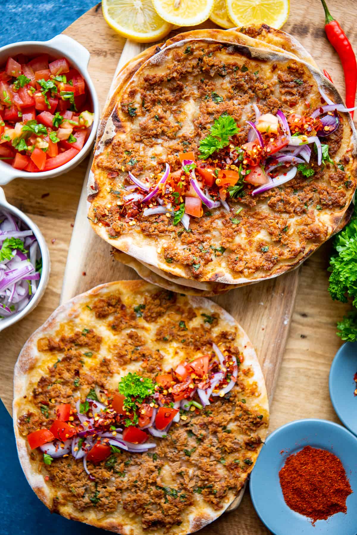 Lahmacun topped with salad accompanied by sliced onions and tomato salad on the side.