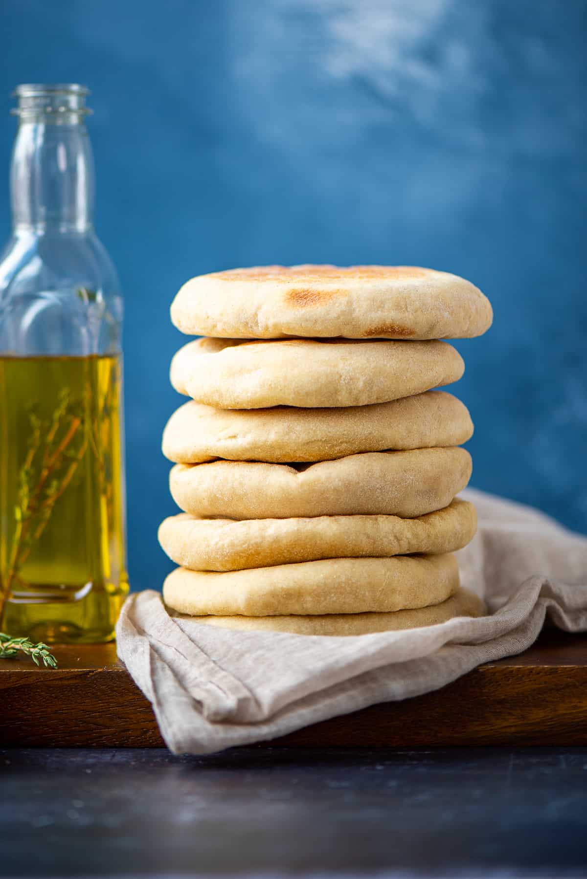 A stack of flatbreads on a napkin and a bottle of olive oil on the side.