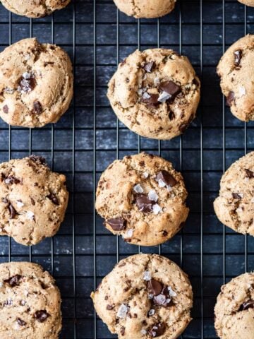 Chocolate chunk tahini cookies with Turkish coffee topped with sea salt on a cooling rack.