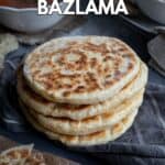 A stack of Turkish bazlama bread on a grey napkin and two bowls of soup behind it.
